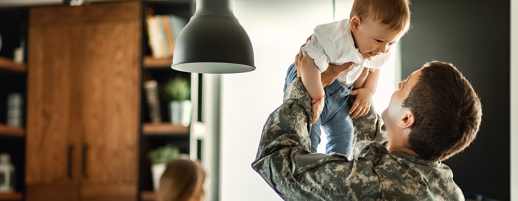 man in military uniform holding baby